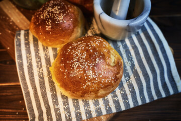 Top view of homemade bun on a chopping board with a striped white kitchen cloth.