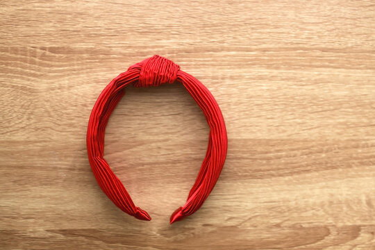 Red headband on wooden background. Flat lay.