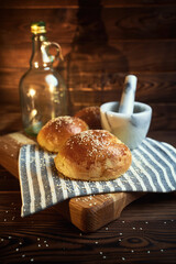 Fresh homemade bun with sesame on cutting board with wooden background