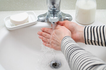 Woman washing hands with soap in the bashroom