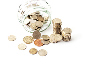 Overturned glass jar full of shined Golden coins on the white background