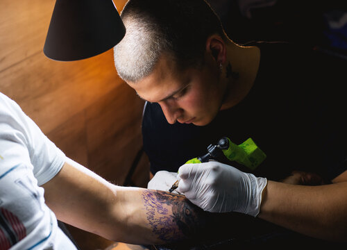 Tattoo Artist making a tattoo on a hand in tattoo studio