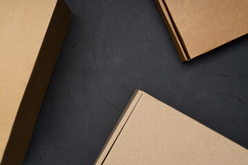 Three cardboard boxes on a black cement background