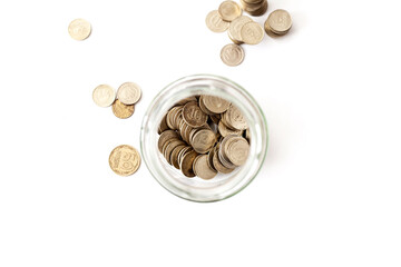 Overturned glass jar full of shined Golden coins on the white background