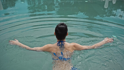 back view of tattooed woman swimming in pool