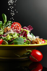 Green salad with greens, tomatoes, walnuts and vegetable oil sprinkled with sesame.