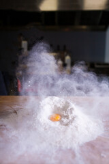 Breaking an egg into flour to make dough on wooden table. breaks the egg into flour. Egg splashing flour. powder explosion in the kitchen. flour and egg dough. Italian Home cooked organic food.