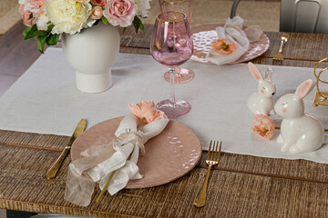 Closeup view of romantic cute table decor with glasses flowers and lit candles. Plates with flowers setup on a wooden table