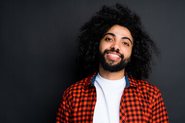 Happy african american man looking at camera and smiling while standing against dark background