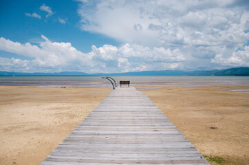 Fototapeta na wymiar Wooden pier with bench with view of lake and sky 