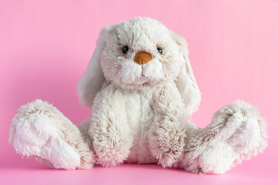 Stuffed bunny on pink background. Easter concept. Cute toy bunny sitting on colored background.