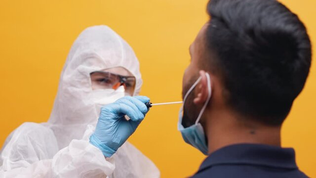 Covid 19 swab test indoors. Nurse in full protecting uniform performing examination. High quality 4k footage