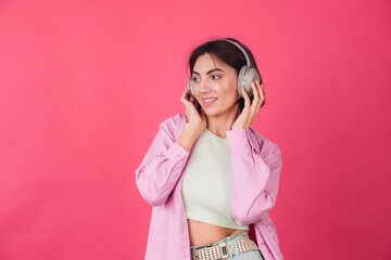 Happy positive woman in headphones on pink red background positive dancing moving enjoying sound