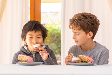  Multi racial children eating ald talking cake inside a house