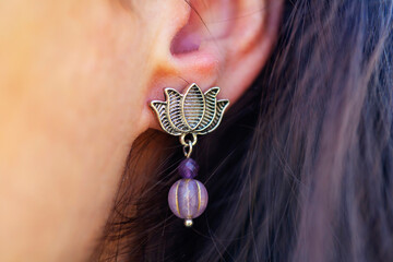 Detail of female ear wearing stone mineral floral shape bead earring