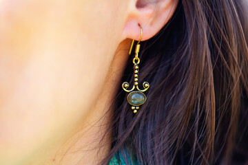 Detail of female ear wearing stone mineral floral shape bead earring