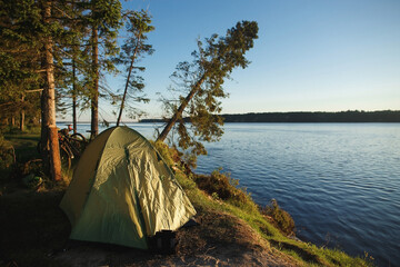 Tent, bike and beautiful camping place with river on the sunrise. Touring cycling concept