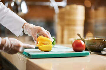 Chef chopping up ripe bell pepper in his kitchen