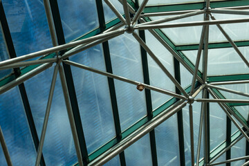 Interior structural support for a large greenhouse enclosure, blue sky beyond, horizontal aspect