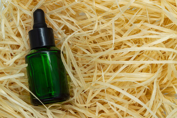 glass bottle for cosmetics on a background of wood shavings copy space