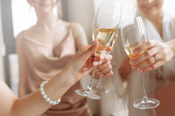 Morning of bride. Gorgeous bride with best bridesmaids are holding glasses and drinking champagne in hotel bathroom near the window. Sexy bridesmaids in exciting negligee. Wedding morning details
