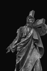 Bottom view of an ancient statue of Jesus Christ with cross. Selective focus on eyes. (faith, religion, God, suffering concept)