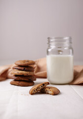 Stack of chocolate chip cookies with glass of milk on light gray background. Selective focus.