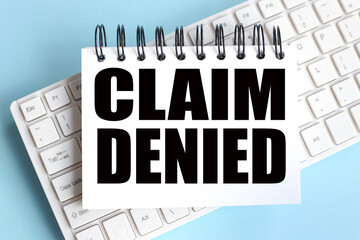 Claim Denied. text on white notepad paper on white keyboard