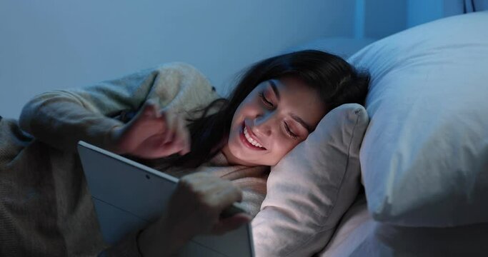 Women are using the tablet computer on the bed before she sleeping at night, Mobile addict concept, Blue light harmful to the eyes.