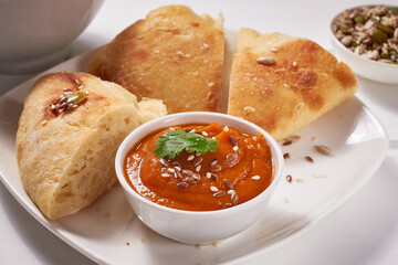 Slices of freshly baked bread and vegetable sauce on a white plate on a white wooden table. Vegan food.