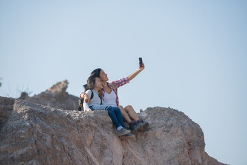 Obraz premium family travel- hikers with backpack looking at mountains, mother with child, Taking selfie,happy mother and girl making self portrait in the mountains, woman holding smartphone camera to take picture.