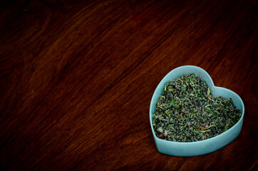 chopped cannabis herb in a heart on wood
