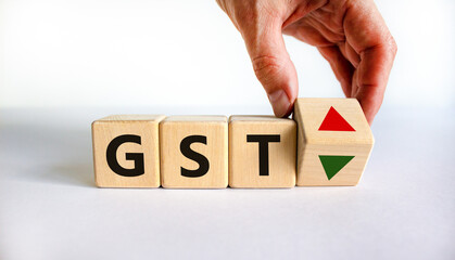 GST, goods and services tax symbol. Businessman holds a cube with up and down icon. Word 'GST'. Beautiful white background. Copy space. Business and growth of GST, goods and services tax concept.
