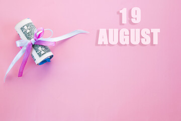 calendar date on pink background with rolled up dollar bills pinned by pink and blue ribbon with copy space. August 19 is the twenty-second day of the month