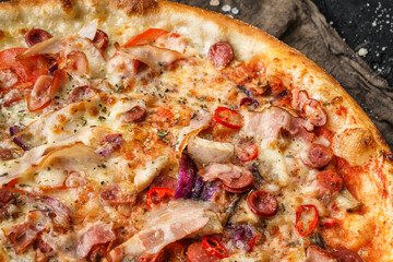 Pizza Pepperoni with prosciutto, sausage, cheese parmesan, tomatoes and onion rings on stone black background. Fast food lunch for picnic company, top view, selective focus