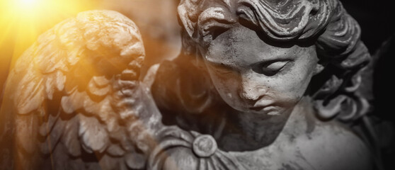 Close up sad guardian angel in sunlight (fragment of an ancient statue)