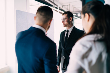 Positive colleagues discussing business near office glass wall