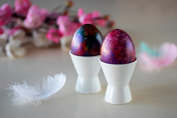 Easter concept. Two decorative eggs in white poached stands on  light background.