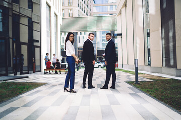 Content young multiracial colleagues standing in street near modern office building