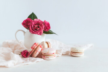 Obraz na płótnie Canvas Tasty french macaroons with pink roses on a white background.