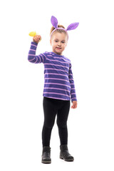 Cute young girl with pink bunny ears hat waving at camera with Eater yellow egg. Full body isolated on white background