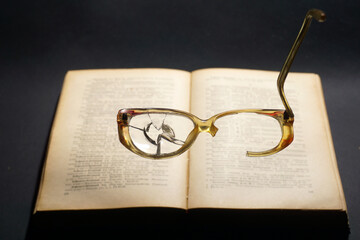  Broken glasses on the background of an open book. The concept of the unsuitability of broken...