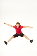Fototapeta na wymiar Cheerful cute boy in sportswear jumping in studio