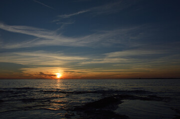 Obraz premium Tramonto sul mare con cielo azzurro e nuvole.