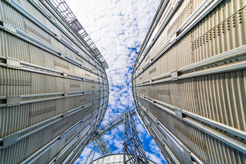Bulk plant storage low angle blue sky. Agricultular metallic corn tower. Steel tank of wheat....