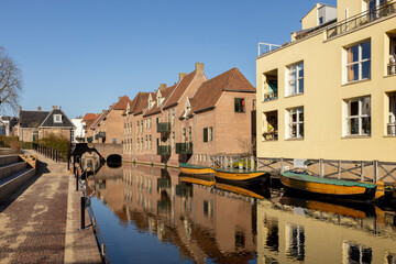 Fototapeta na wymiar Historic facades of medieval city Zutphen in The Netherlands with whisper boats reflected in the water of river Berkel against a clear blue sky