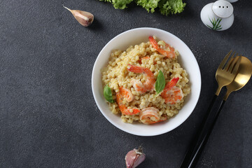 Homemade pasta ptitim with shrimps,garlic and basil in white plate on gray table. Top view. Copy space