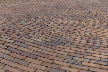 Undulating background of a street paved in red bricks, running bond pattern, horizontal aspect
