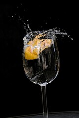 Lemon slice falls in glass of water