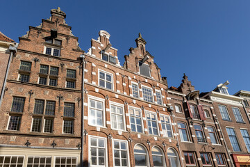 Fototapeta na wymiar Looking up at typical historic medieval exterior facades in Hanseatic city center Zutphen, The Netherlands, against a clear blue sky. Europe tourism destination.